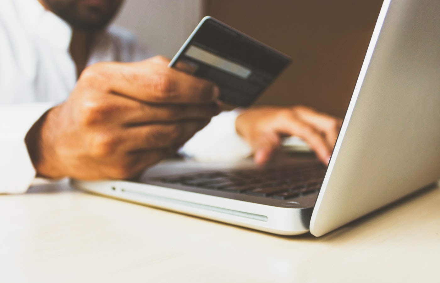 Pessoa utilizando cartão e computador em transação digital
